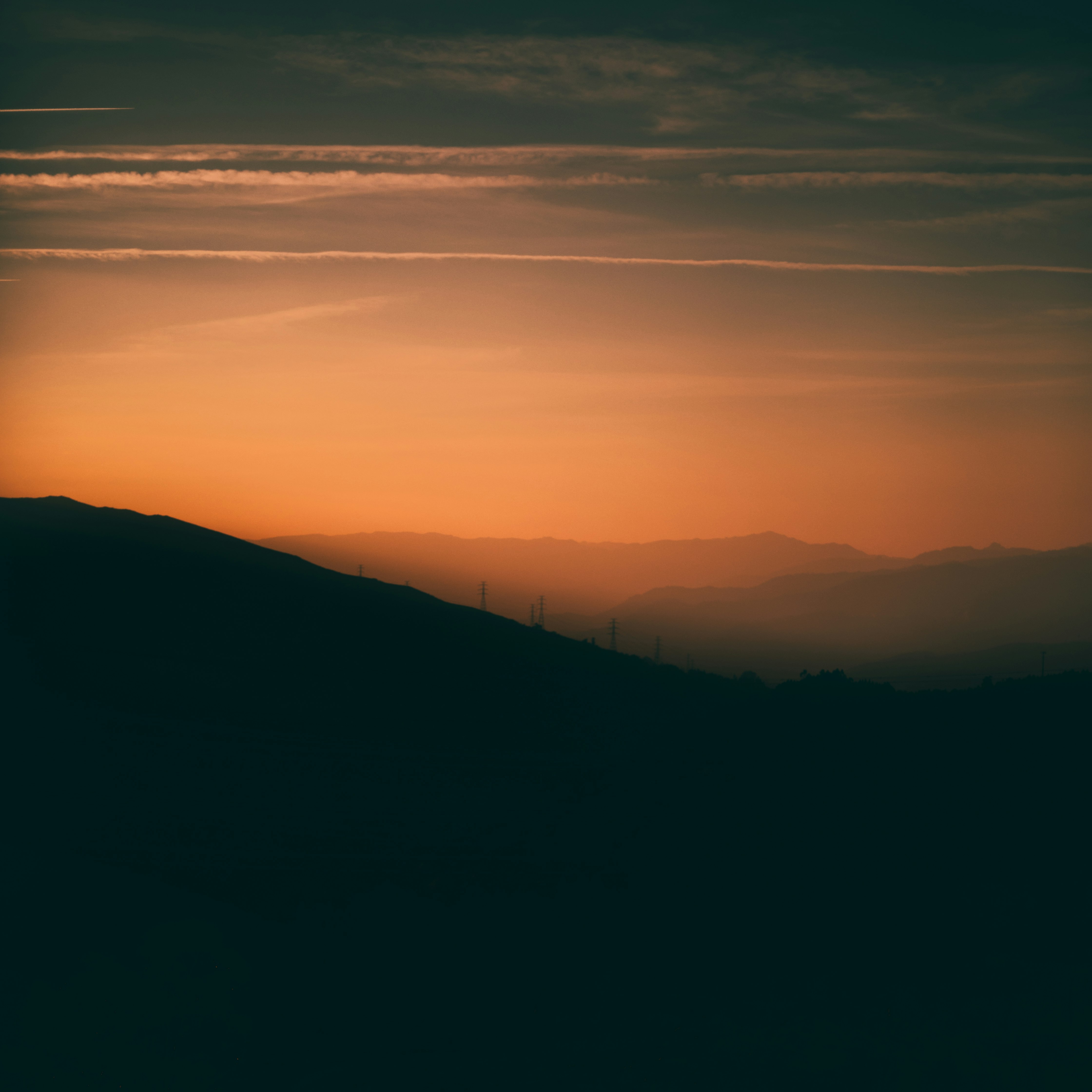 silhouette of mountain under orange and gray skies